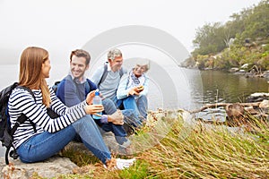 A senior and a young adult couple sitting together by a lake