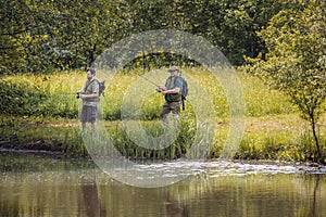 Senior and young fishermen on the river shore