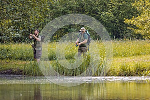 Senior and young fishermen on the river shore