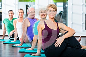 Senior and young people doing sit-up in fitness gym