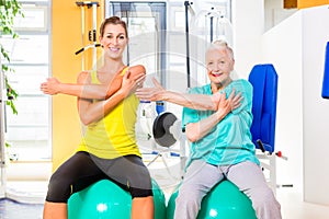 Senior and young woman working out in fitness gym