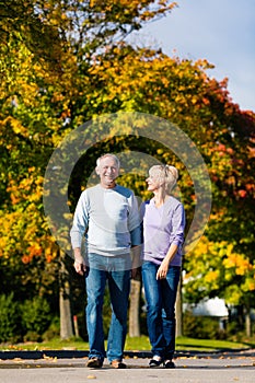 Seniors in autumn or fall walking hand in hand