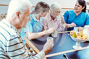 Seniors and caregivers having coffee time in the nursing home