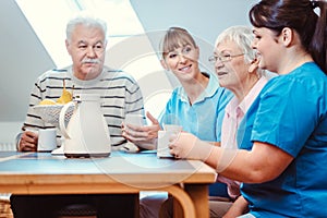 Seniors and caregivers having coffee time in the nursing home photo