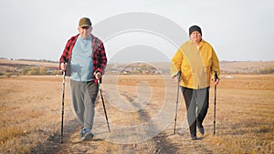 Seniors couple nordic walking in autumn forest.