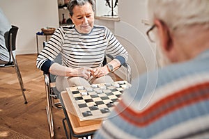 Seniors couple playing checkers at nurse home together