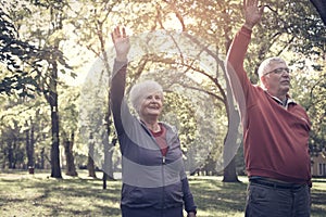 Seniors couple stretching arms and exercising together in