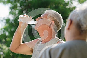 Seniors drinking water after fitness in park