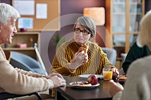 Seniors enjoying lunch at common table in retirement home