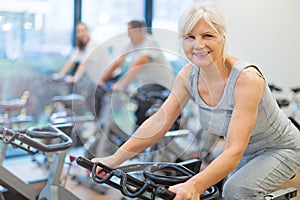 Seniors on exercise bikes in spinning class at gym