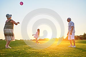 Seniors with grandchild playing ball.