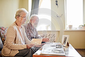 Seniors looking at their photo album at home