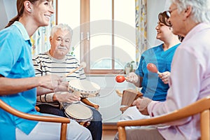 Seniors in nursing home making music with rhythm instruments