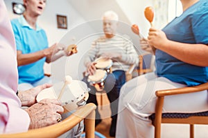 Seniors in nursing home making music with rhythm instruments photo