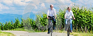 Seniors riding bicycle in vineyard together