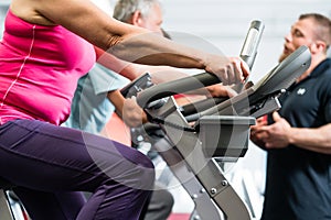 Seniors spinning with personal trainer at the gym