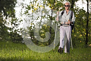 Seniors Sports and Healthy Lifestyle Concepts. Mature Caucasian Woman Having Fitness Nordic Walking Exercise with Backpack in