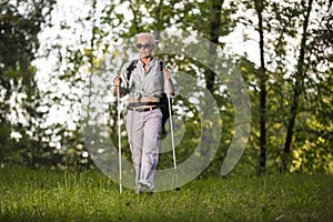 Seniors Sports and Healthy Lifestyle Concepts. Mature Caucasian Woman Having Fitness Nordic Walking Exercise with Backpack in