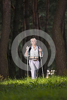 Seniors Sports and Healthy Lifestyle Concepts. Mature Caucasian Woman Having Fitness Nordic Walking Exercise with Backpack in Deep