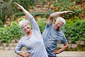 Seniors staying active. a senior couple doing yoga together outdoors.