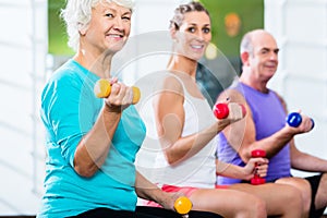 Seniors with trainer in gym at sport lifting barbell