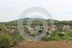 Senkvice, Slovakia - April, 2011: small houses, green fields and hills view from railway carriage.