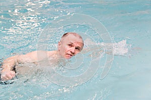 Senoir male swimming in indoor pool.