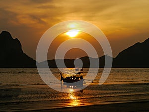 Sensational golden sunset over the beautiful Pak Meng beach with a traditional Thai Long-tail boat