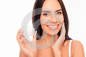Sensetive pretty woman holding jar of cream and touching her face