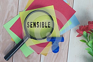 Sensible word on colorful adhesive paper with magnifying glass. photo
