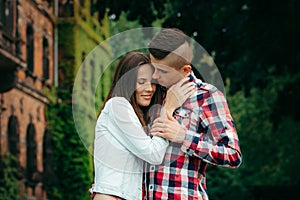 Sensitive outdoor portrait of the loving couple tenderly hugging. The young man is stroking the hand of his lover.