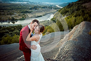 Sensitive portrait of the adorable newlywed couple hugging at the background of the magnificent landscape during the