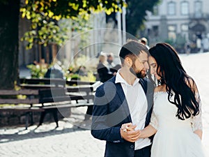 Sensitive portrait of the tender beautiful newliwed couple softly hugging and holding hands while standing head-to-head