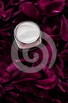 Sensitive skincare moisturizer cream on purple flower petals background, natural science for skin