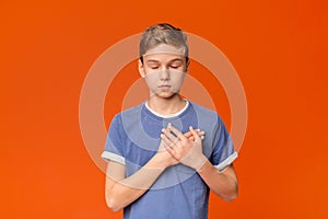 Sensitive teenage boy pressing hands to chest being grateful