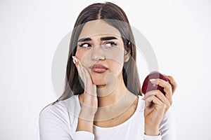 Sensitive Teeth. Young Woman Having Tooth Pain Eating Apple Standing On Gray Studio Background. woman who feels toothpain because