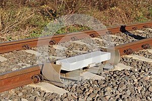 Sensor signaling the passage of the train on the railway track to activate the alarm at a road crossing. Mound of coarse gravel