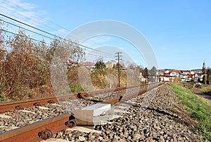 Sensor signaling the passage of the train on the railway track to activate the alarm at a road crossing. Mound of coarse gravel