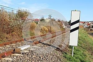Sensor signaling the passage of the train on the railway track to activate the alarm at a road crossing. Mound of coarse gravel