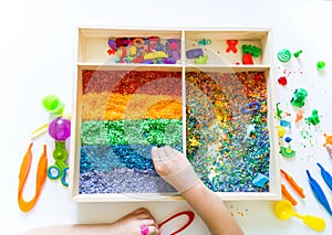 Sensory box with rainbow rice inside. Montessori material baby photo