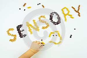 Sensory word written of popcorn, beans, pasta and children hands. Sensory play for child at home. Activities Montessori