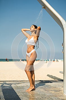 Sensous young woman taking shower at the beach