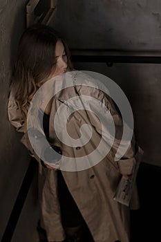 Sensual attractive brunette in trench coat in dark loft room. urban lifestyle concept