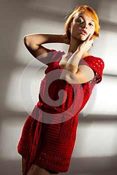 Sensual beautiful blonde woman posing in red dress. Girl with long curly hair.