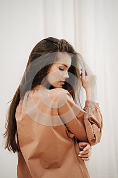 Sensual beautiful woman wearing pale brown dress. View from the side.