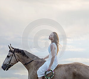 Sensual blond woman riding a brown stallion