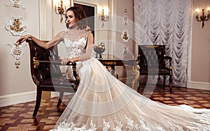 Sensual brunette bride in luxury wedding dress over classic interior