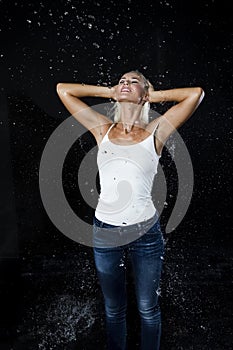 Sensual Caucasian Blond Female in White Shirt Posing Under The Water Rain Drops Against Black Background