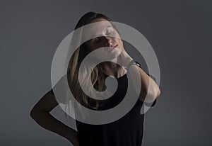 Sensual close up portrait of a young woman closing her eues in satisfaction and pleasure on a dark background. A charming languid