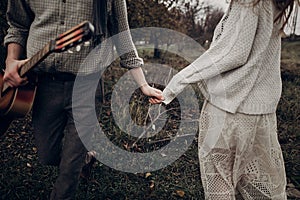 Sensual couple, gypsy woman in white boho dress holding hands wi